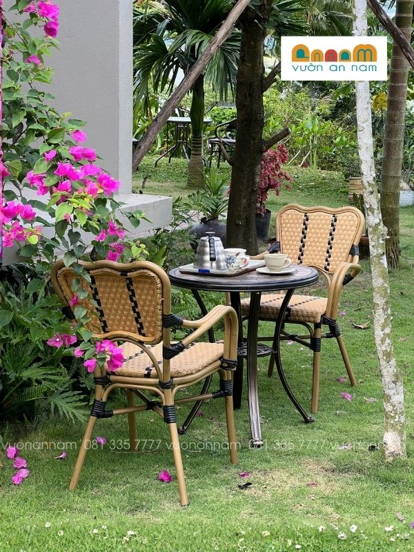 bộ 1 bàn và 2 ghế giả mây đặt tại không gian sân vườn